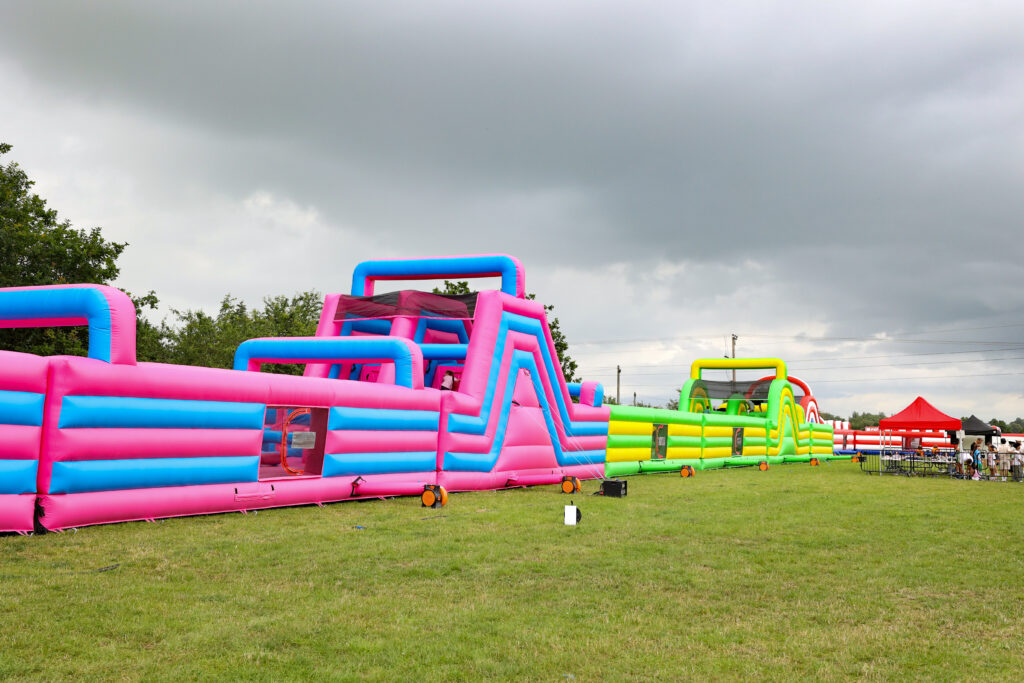 Action Arena inflatable obstacle courses on grass at a family event in Plymouth.
