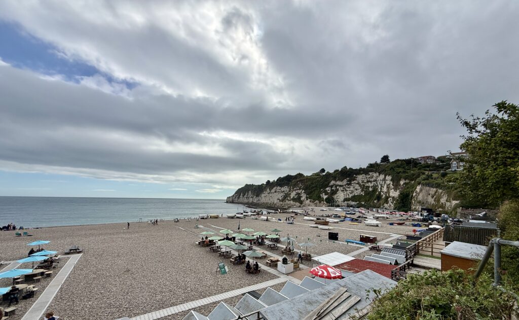 Beer Beach in Devon with fishing boats, beach cafés and white chalk cliffs.