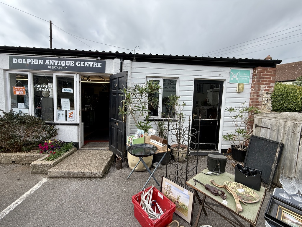 Dolphin Antique Centre in Beer, Devon, with furniture, pictures and collectables displayed outside the shop.