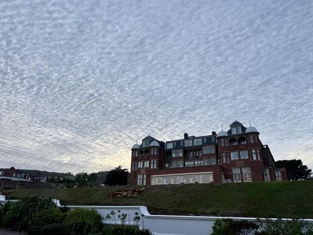 The Victoria Hotel in Sidmouth, Devon, overlooking the seafront and Jurassic Coast beneath a dramatic cloud filled evening sky.