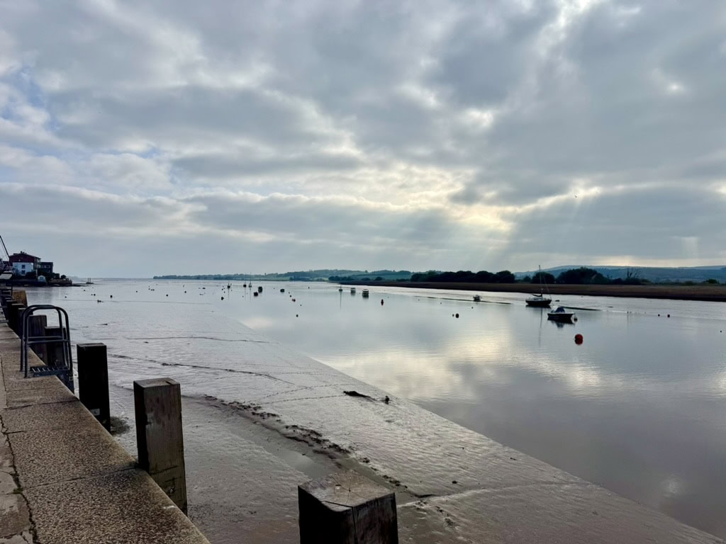 River Exe at Topsham, with boats moored on the calm estuary beneath a cloudy sky.