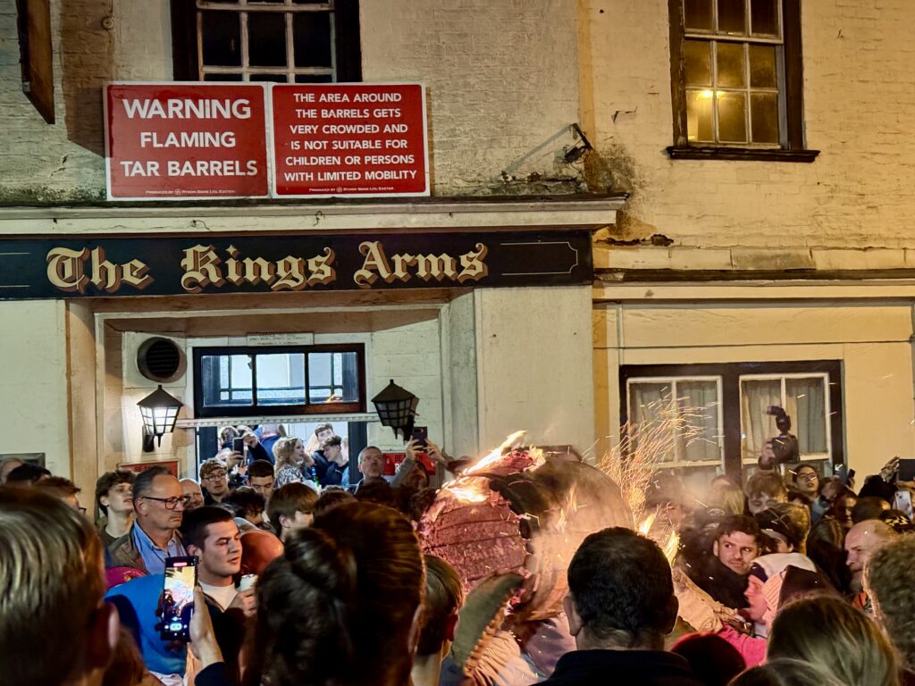 Flaming tar barrel carried through crowds outside The Kings Arms during the Ottery St Mary Tar Barrels.