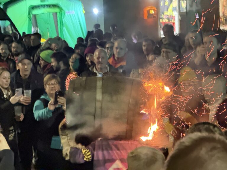 A burning tar barrel being carried through crowds in Ottery St Mary.