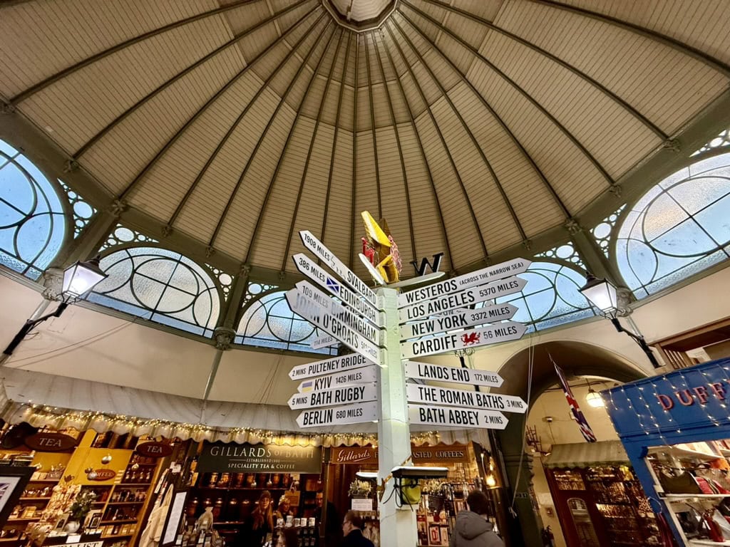 Interior of Bath Guildhall Market with its historic domed roof, independent stalls and signpost to Bath attractions