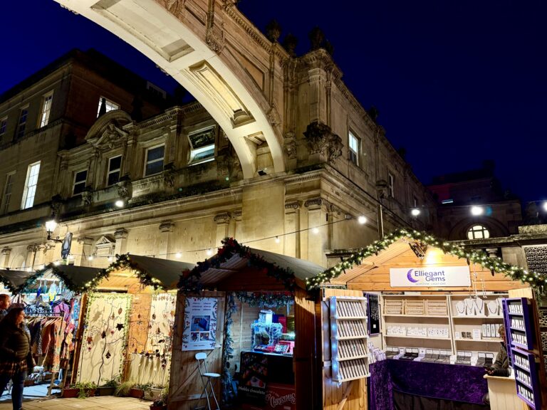 Bath Christmas Market 2026 wooden chalets illuminated at night beneath Bath's historic Georgian architecture
