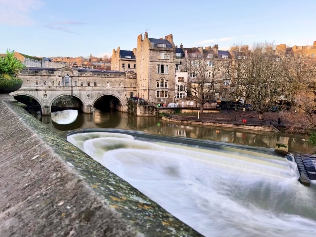 Pulteney Bridge spanning the River Avon in Bath, with the weir in the foreground and historic city buildings beyond