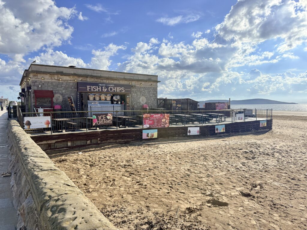 Traditional fish and chip takeaway beside the beach at Weston-super-Mare, with outdoor seating overlooking Weston Bay and Brean Down.