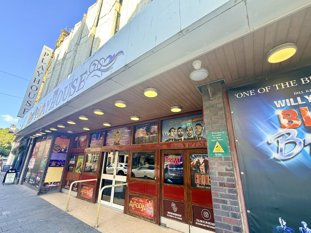 Front entrance of the Playhouse Theatre in Weston-super-Mare, with posters advertising upcoming shows and performances.