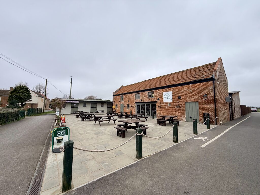 Café 33 on Weston Road in Brean, a red brick building with outdoor picnic tables and seating along the Brean Down Way route.