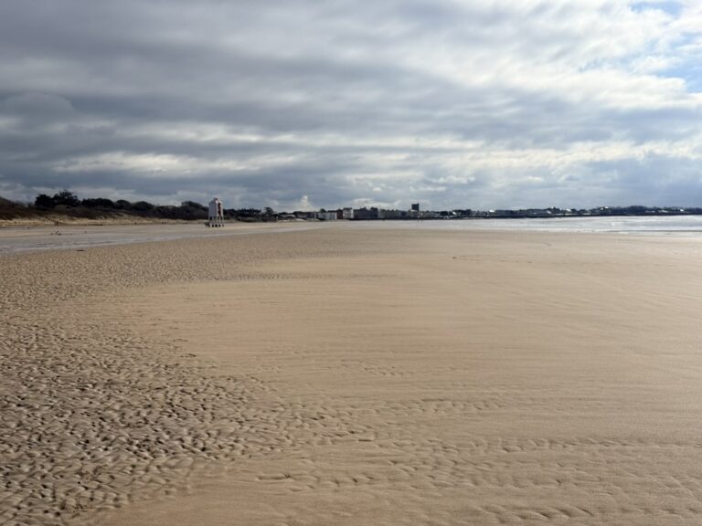 Burnham-on-Sea beach in Somerset with the Low Lighthouse and wide Bristol Channel horizon at low tide.