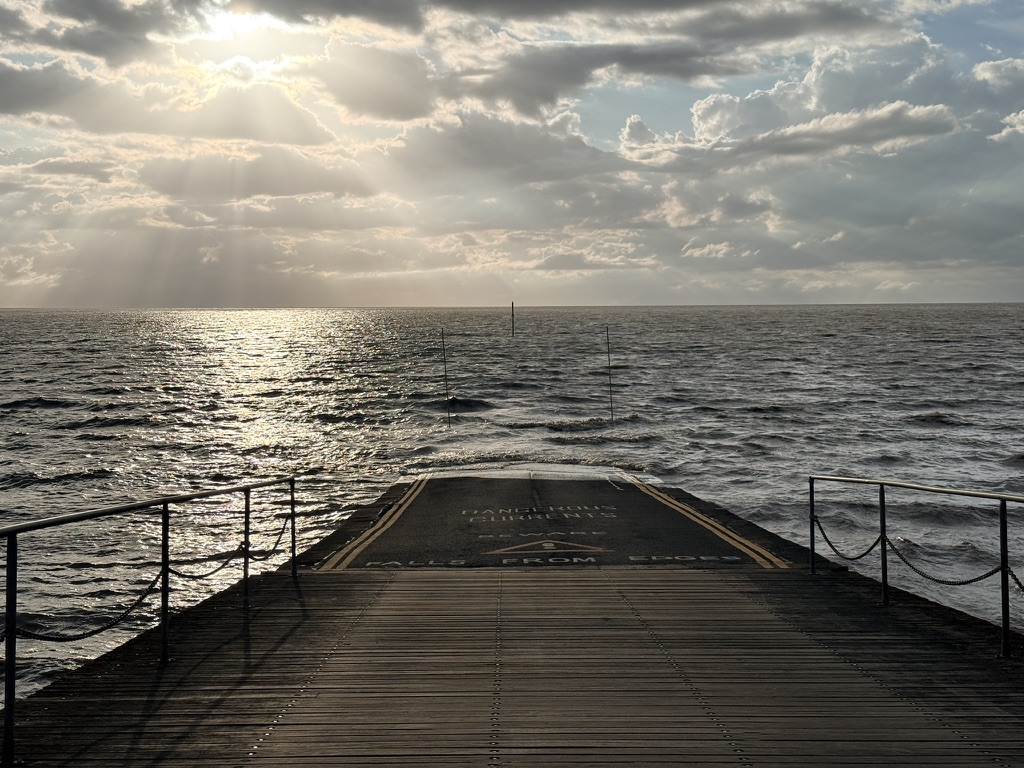 Burnham-on-Sea’s old jetty at high tide, looking across the Bristol Channel beneath sunlit clouds.