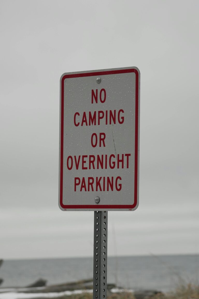 Sign prohibiting camping and overnight parking near a beach area.