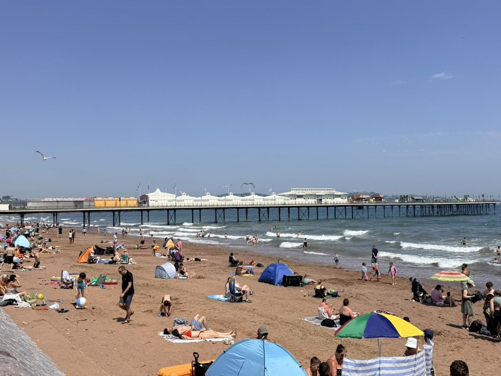 Paignton Beach and Paignton Pier on a busy summer day in Torbay, with families on the sand and views across the main display area used during the Torbay Airshow 2026.

