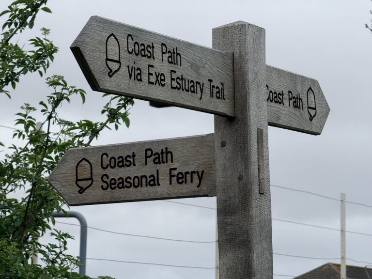 Fingerpost sign for the South West Coast Path and Exe Estuary Trail near Starcross, Devon, showing directions for the seasonal ferry and coastal walking routes.