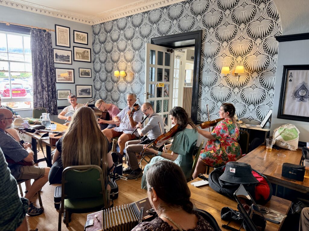 Musicians playing fiddles, whistles and a melodeon during an informal folk session inside the Bedford Hotel in Sidmouth