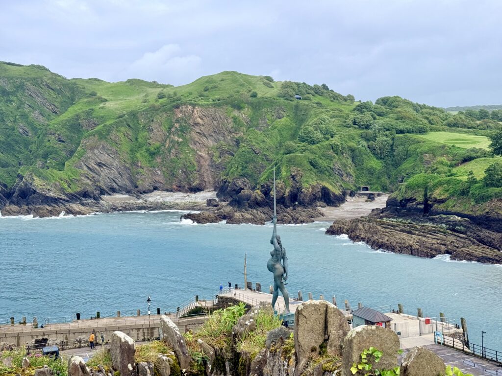 Damien Hirst's Verity sculpture overlooking Ilfracombe Harbour in North Devon, with the rugged coastline forming the background.