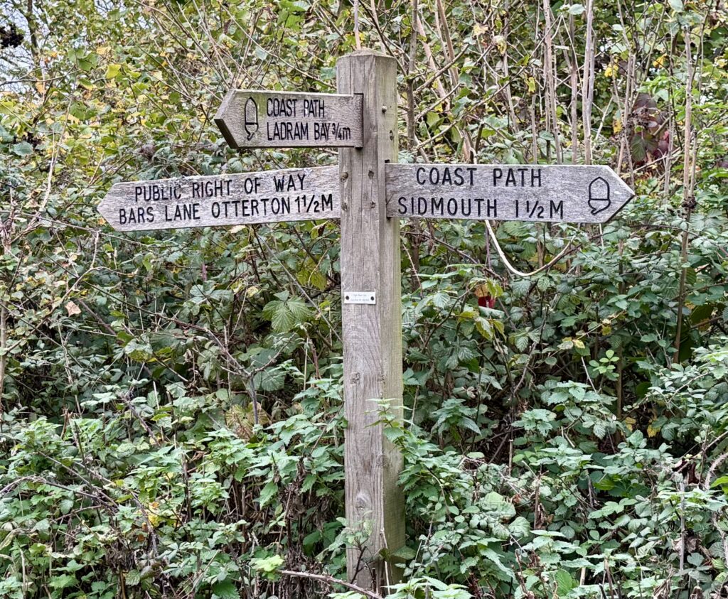 South West Coast Path signpost near Sidmouth showing directions to Ladram Bay, Otterton and Sidmouth in East Devon.