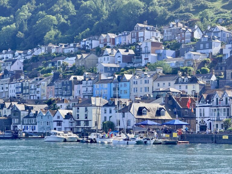 Colourful houses and buildings on Dartmouth’s steep hillside above the River Dart, seen from across the water in Devon, England.