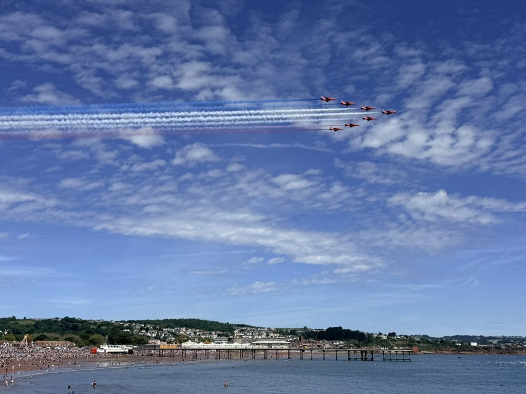 Red Arrows display team flying over Paignton Pier and Paignton Beach in Devon during the English Riviera Airshow.