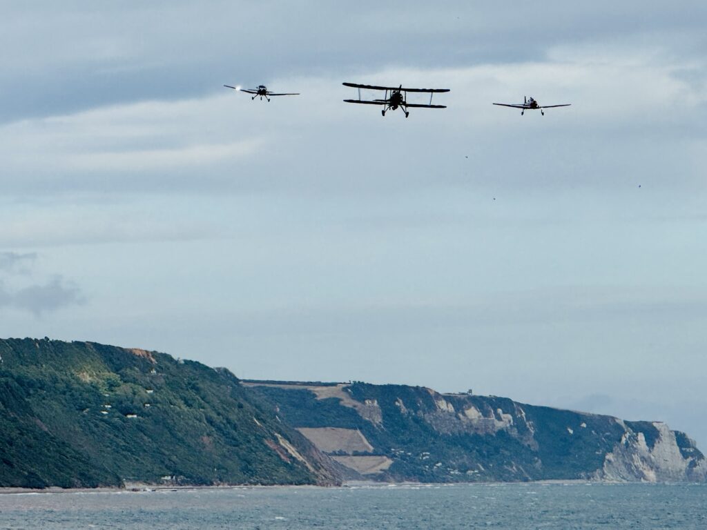 Navy Wings Fairey Swordfish, de Havilland Chipmunk and Scottish Aviation Bulldog flying in formation over the Devon coast during Sidmouth Airshow 2026.