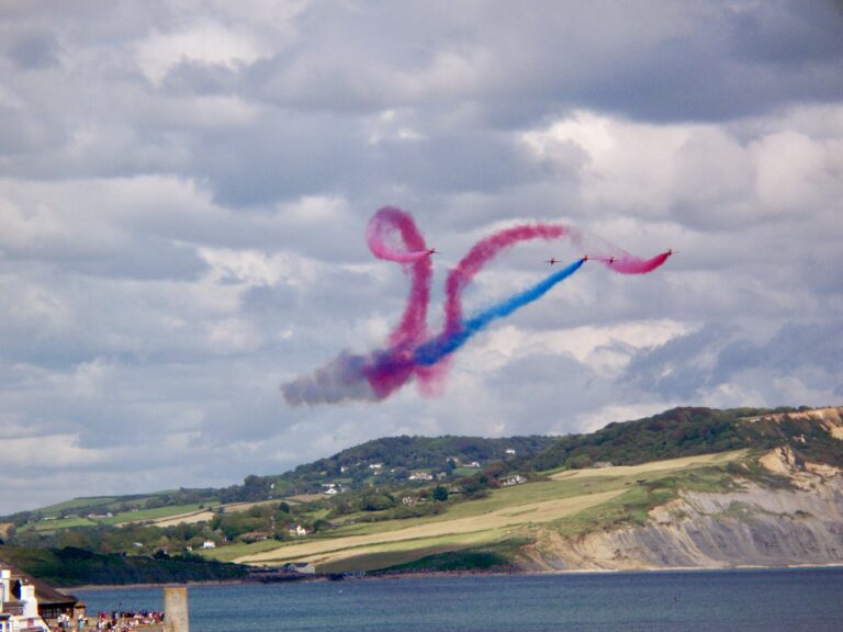 Red Arrows performing with coloured smoke over Charmouth Beach near Lyme Regis