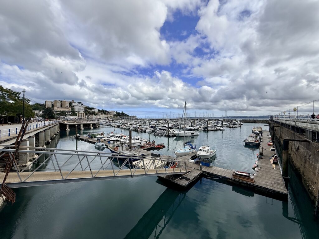 Boats and yachts moored in Torquay Harbour and marina, with waterfront buildings beneath dramatic clouds