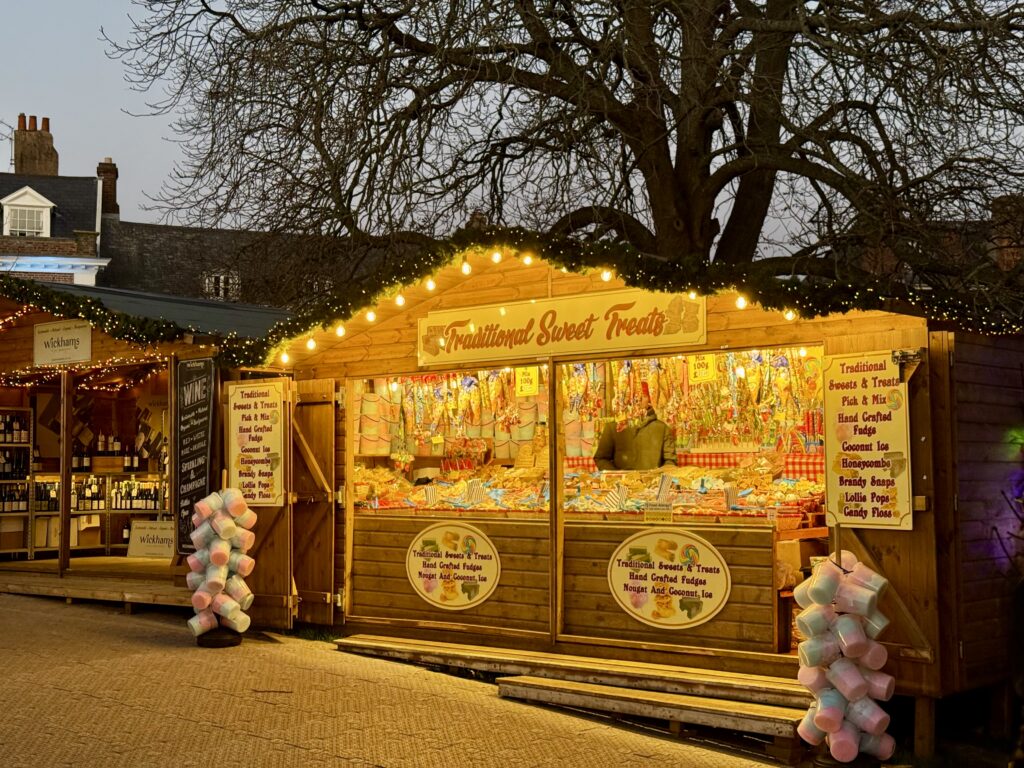 Illuminated wooden chalet selling traditional sweets and candyfloss at Exeter Christmas Market