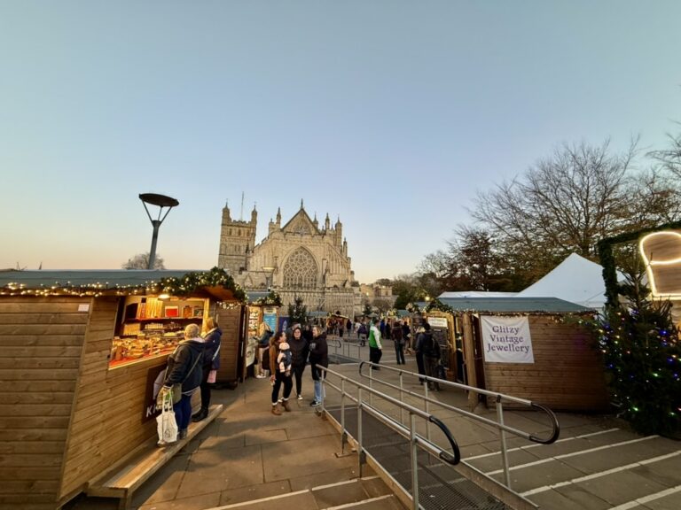 Exeter Christmas Market chalets and visitors on Cathedral Green, with Exeter Cathedral beyond