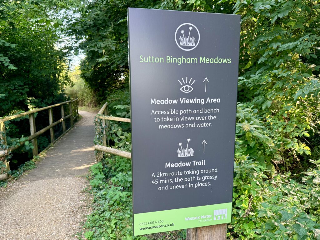 Sutton Bingham Meadows sign beside the accessible path, directing visitors to the viewing area and 2 km Meadow Trail.