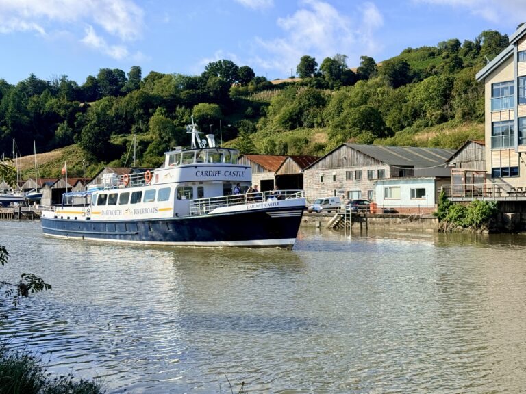 Dartmouth River Boats vessel Cardiff Castle cruising past riverside boatyards and wooded hills on the River Dart