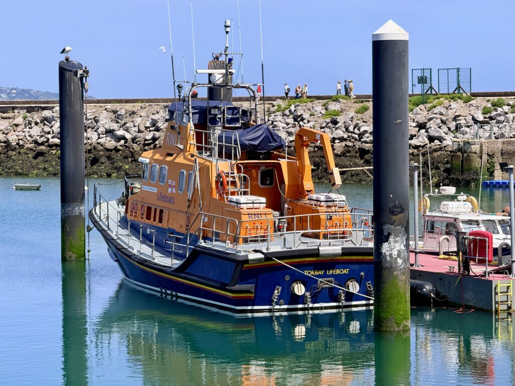 Torbay RNLI lifeboat moored at Brixham Harbour with the breakwater behind.