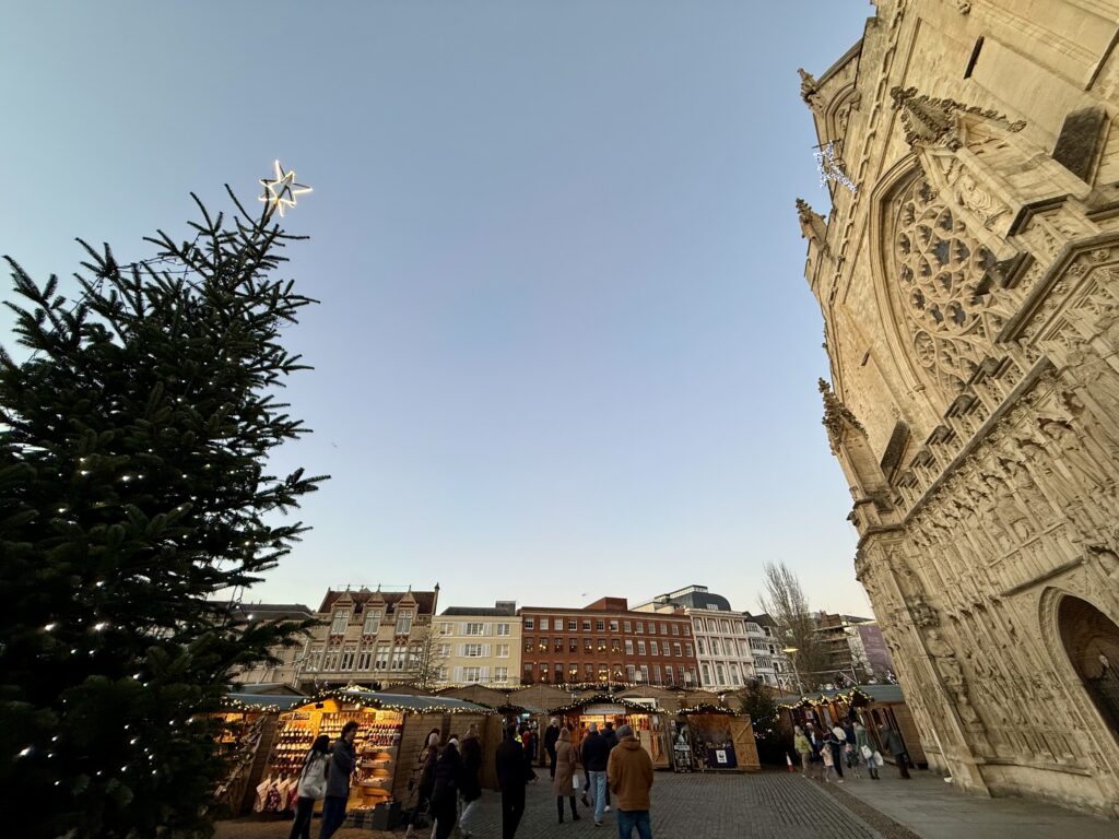 Christmas tree and wooden market chalets beside the west front of Exeter Cathedral