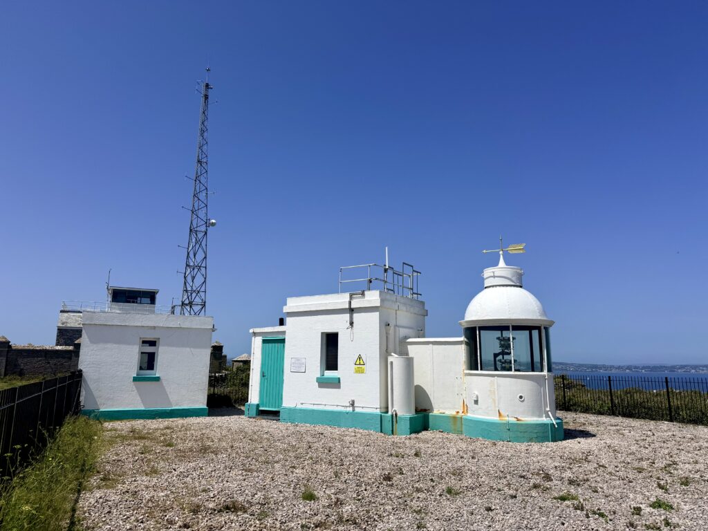 White lighthouse buildings at Berry Head near Brixham beneath a clear blue sky.