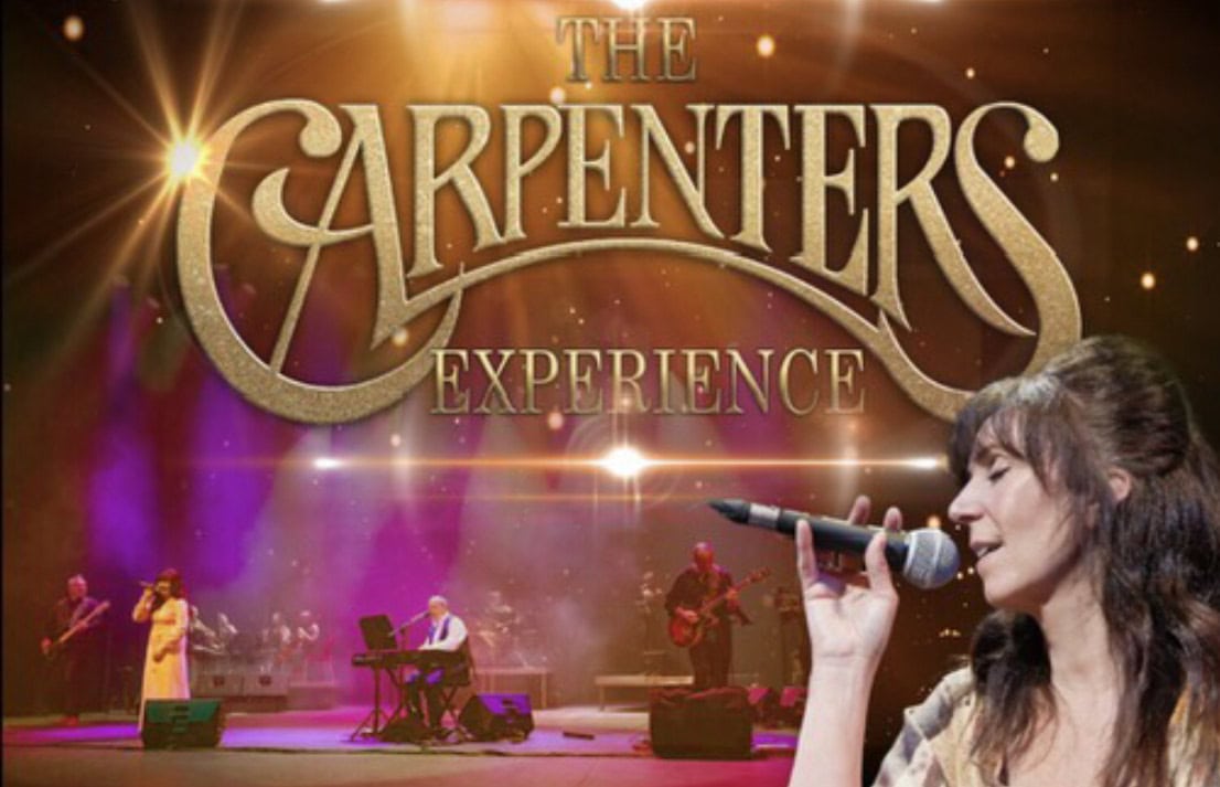 Promotional image for The Carpenters Experience showing vocalist Maggie Nestor singing beside the band performing under colourful stage lights.