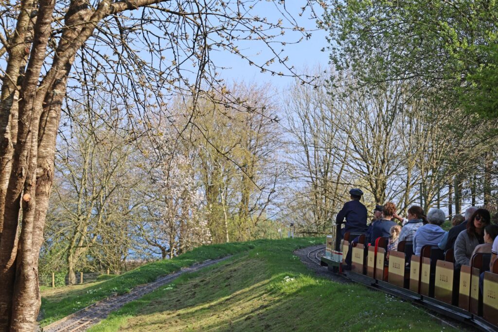 Passengers riding the Beer Heights Light Railway through the wooded gardens at Pecorama in Beer, Devon