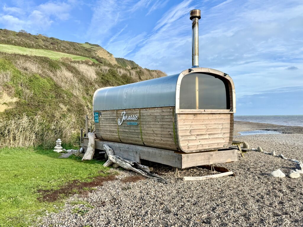 Barrel shaped wood fired Jurassic Saunas cabin beside the pebble beach and cliffs at Branscombe, Devon.