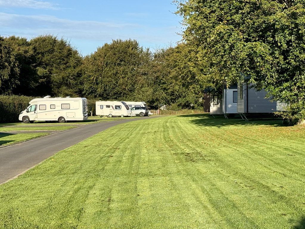 Motorhomes, touring caravans and static holiday homes set among spacious grass pitches and trees at Stowford Farm Meadows