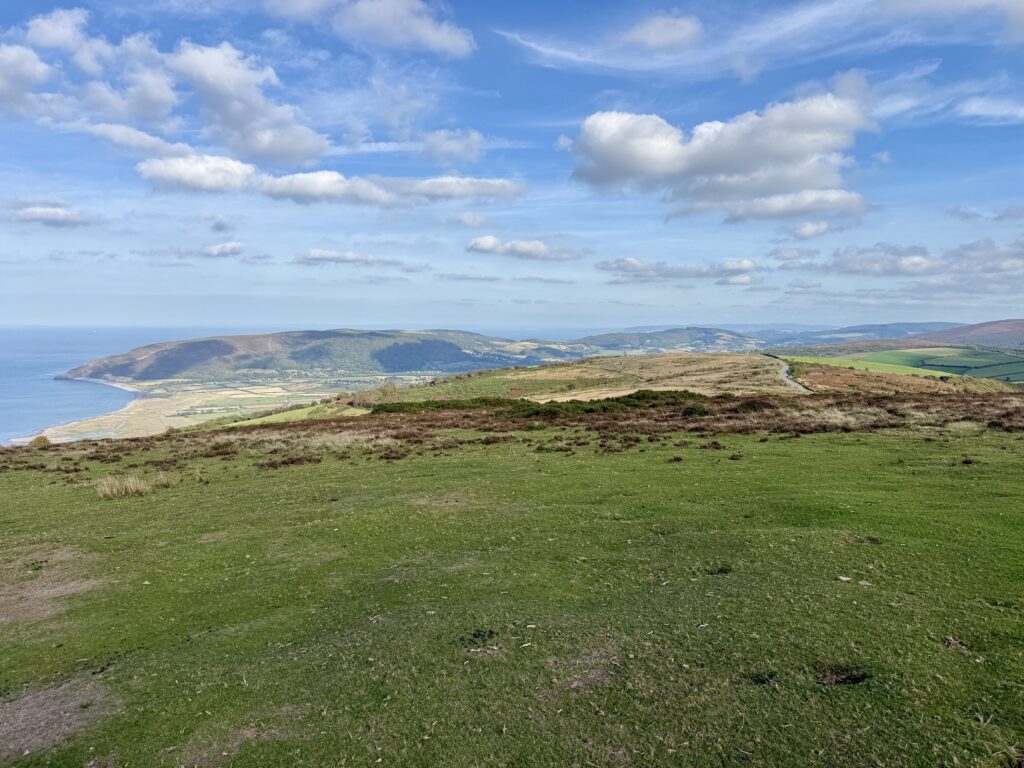 Panoramic view across Exmoor with rolling moorland, wooded valleys and the North Devon coast beside the A39
