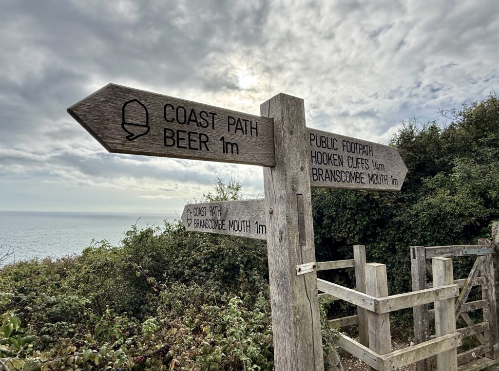 South West Coast Path signpost pointing towards Beer, Branscombe Mouth and Hooken Cliffs.