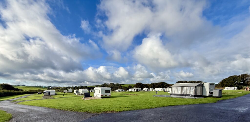 Touring caravans and awnings on large grass and hardstanding pitches at Stowford Farm Meadows under a dramatic North Devon sky.