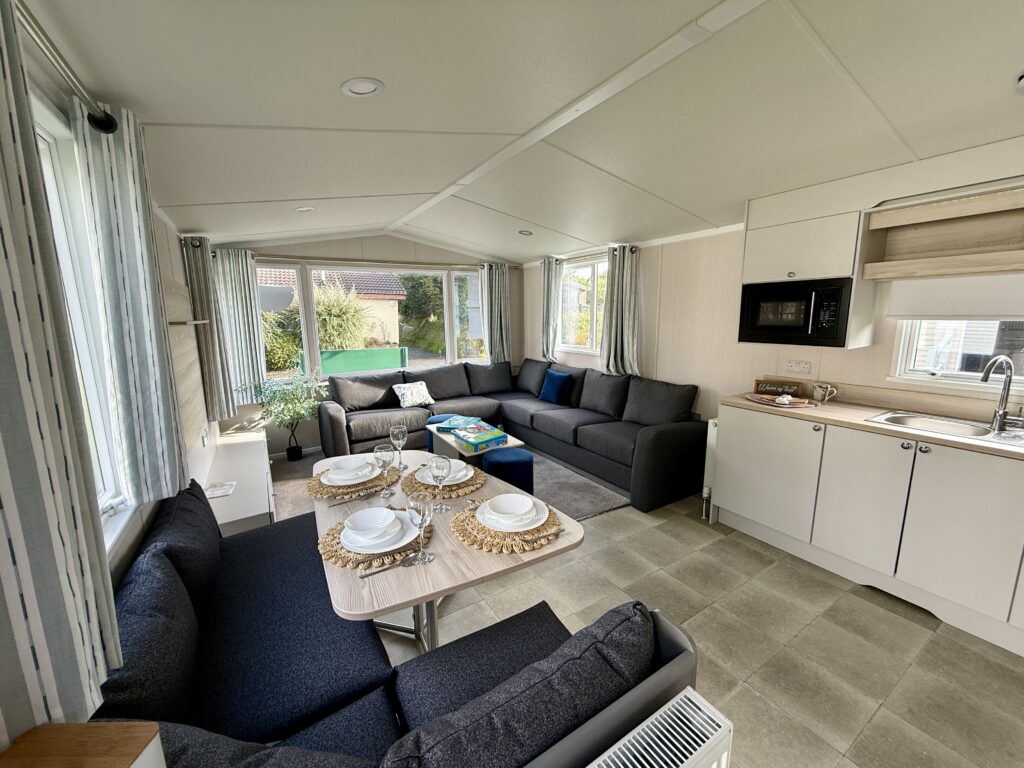 Interior of a modern static holiday caravan at Stowford Farm Meadows with open-plan lounge, dining area and fitted kitchen.