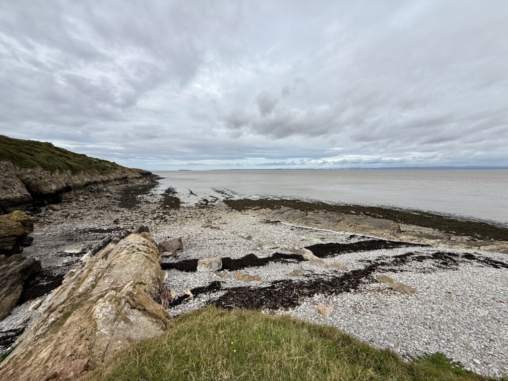 Secluded pebble cove below Sand Point with limestone rocks and views across the Bristol Channel