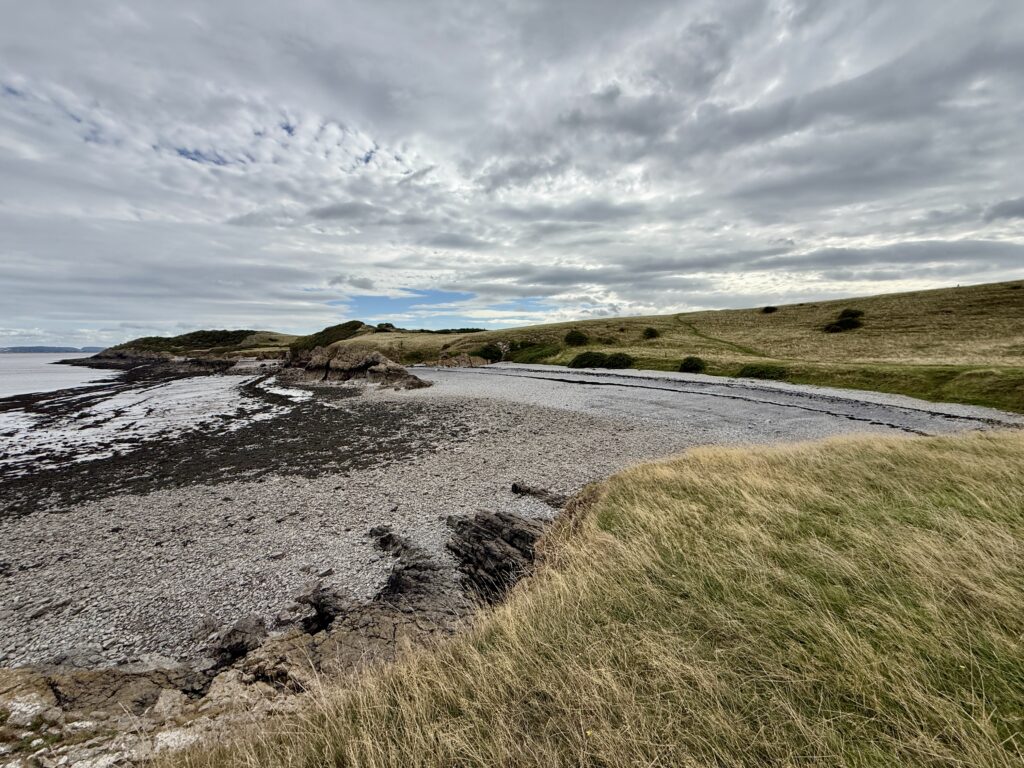 Secluded pebble cove and grassy slopes on Middle Hope near Sand Point