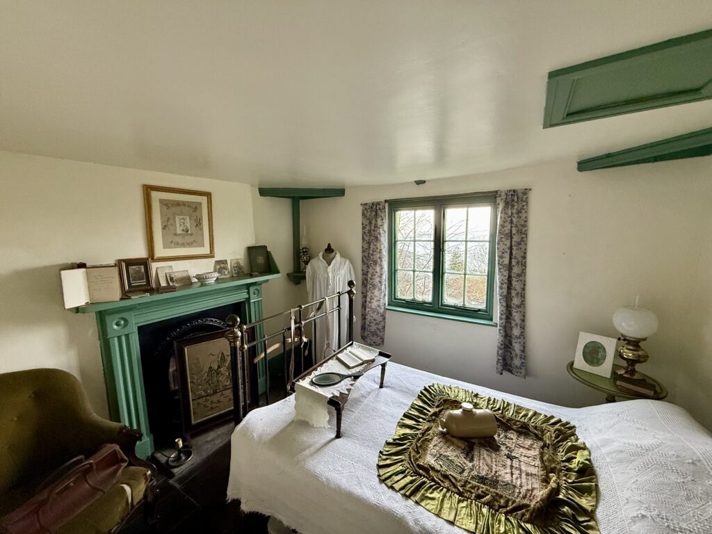 Interior of a traditional Clovelly cottage with a bed, fireplace and period furnishings overlooking the village.