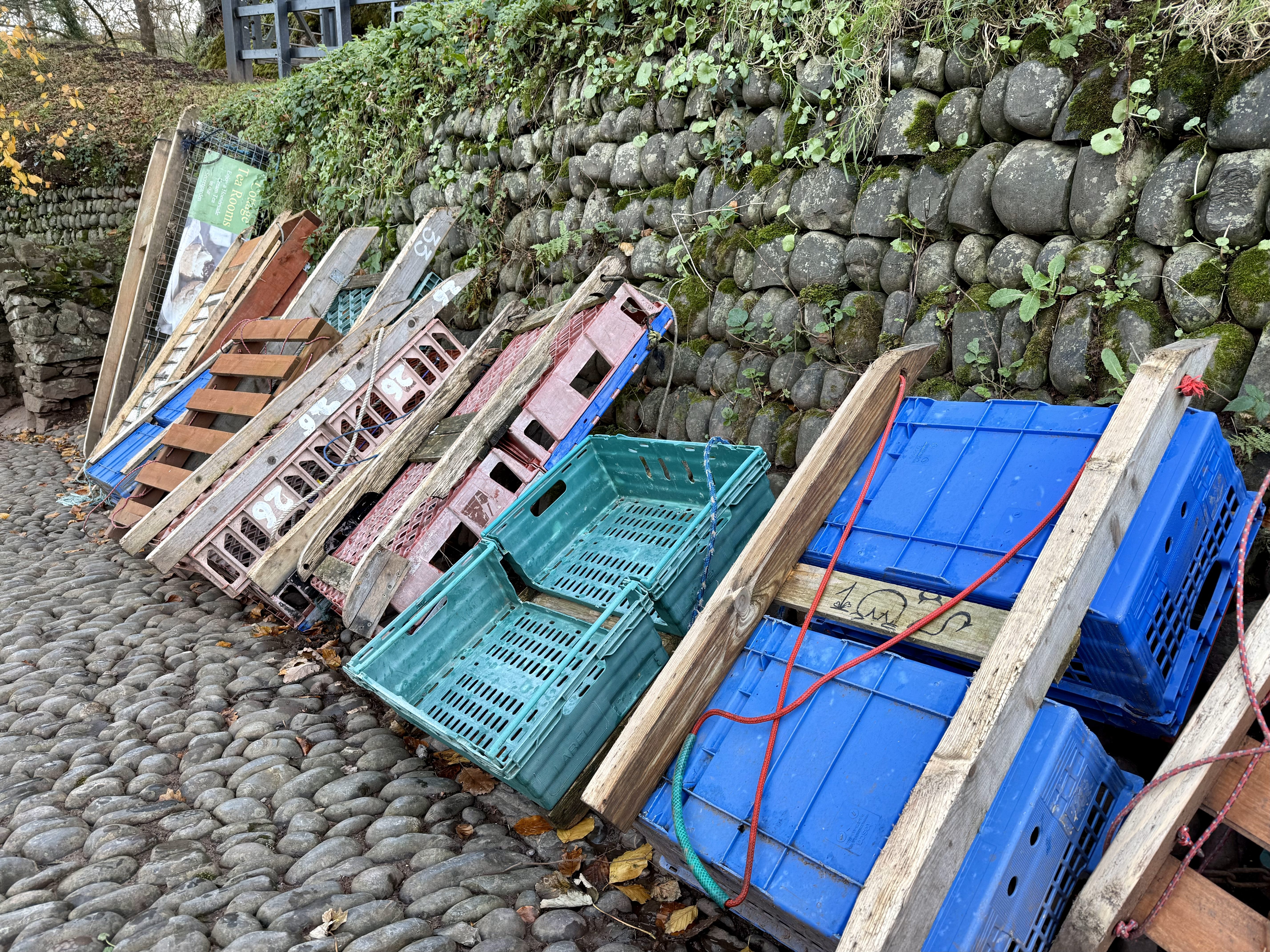 Traditional wooden sledges loaded with crates and boxes beside Clovelly's cobbled street.