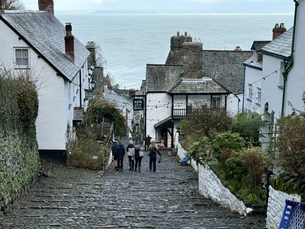 Looking down Clovelly's steep cobbled High Street between white cottages towards the sea.