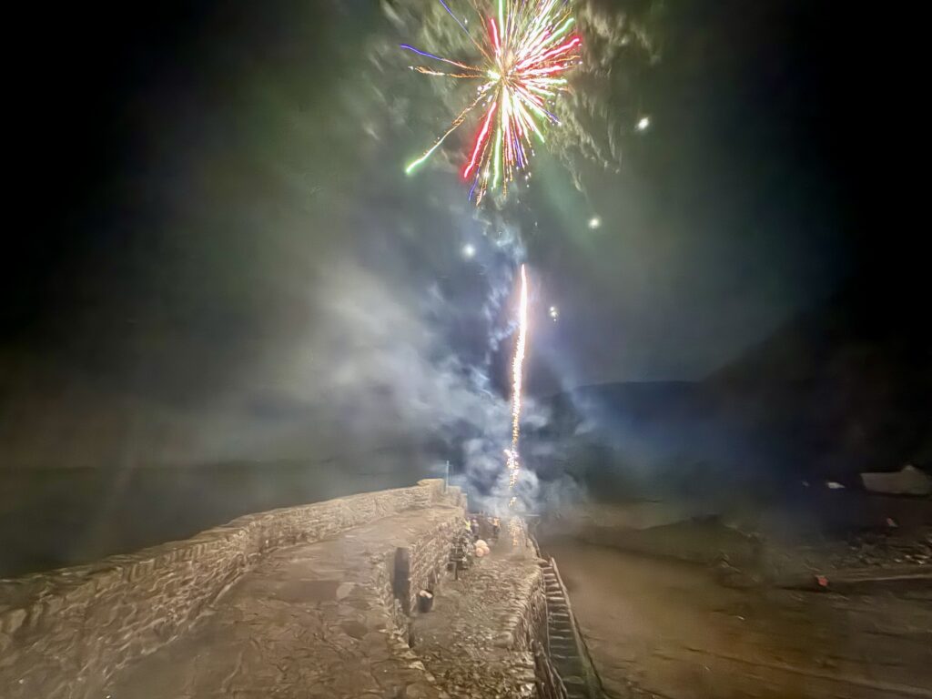 Fireworks exploding above Clovelly harbour at night during the Christmas light switch-on.