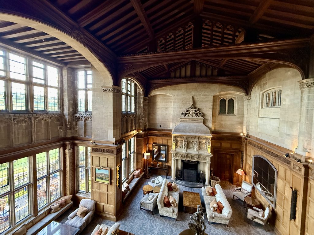 The Cathedral Room at Bovey Castle, with its Minstrels' Gallery, vaulted timber ceiling, tall leaded windows and ornate stone fireplace.